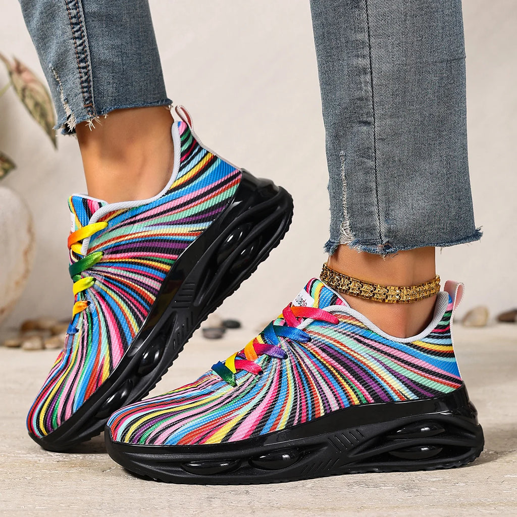 Person wearing multicolored striped sneakers with black soles and rainbow-colored laces