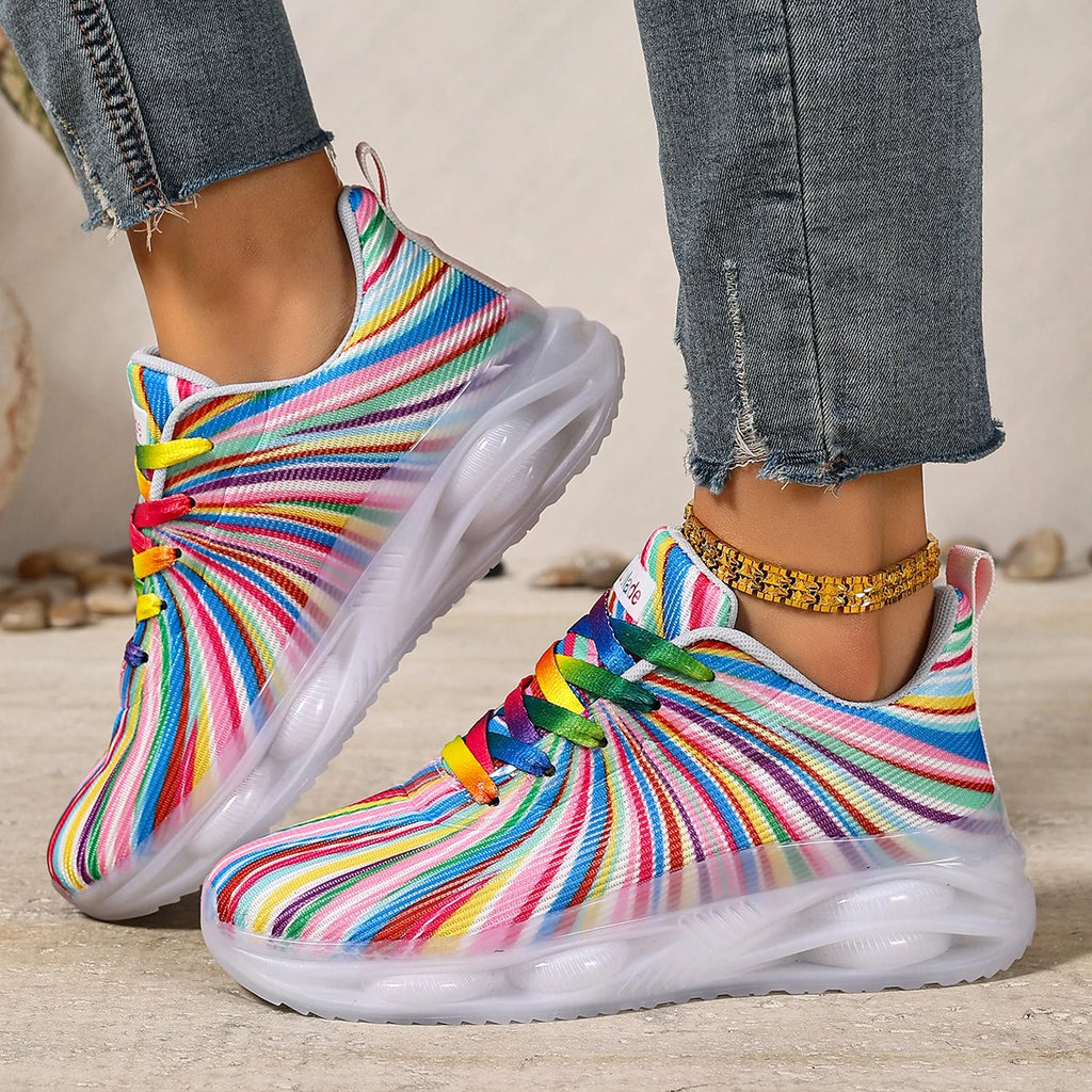 Two rainbow-striped sneakers with multicolored laces, shown on feet from the side