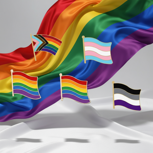 Five LGBT pride flag enamel pins arranged over draped rainbow fabric
