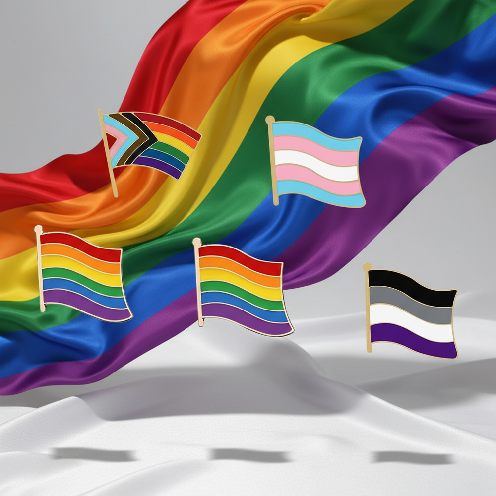 Five LGBT pride flag enamel pins arranged over draped rainbow fabric