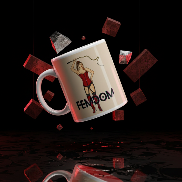 Femdom Mug: A bold, glossy white ceramic mug featuring a confident woman in a red corset with the word “FEMDOM,” surrounded by floating red and metallic blocks, radiating LGBTQIA+ pride and empowerment.