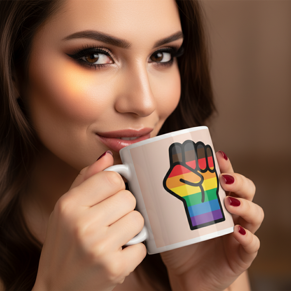 Woman holds BLM LGBT Resist Mug with pride flag fist design, showcasing queer empowerment. Her deep red nails contrast the white ceramic, embodying bold self-expression and joy from Queer In The World.