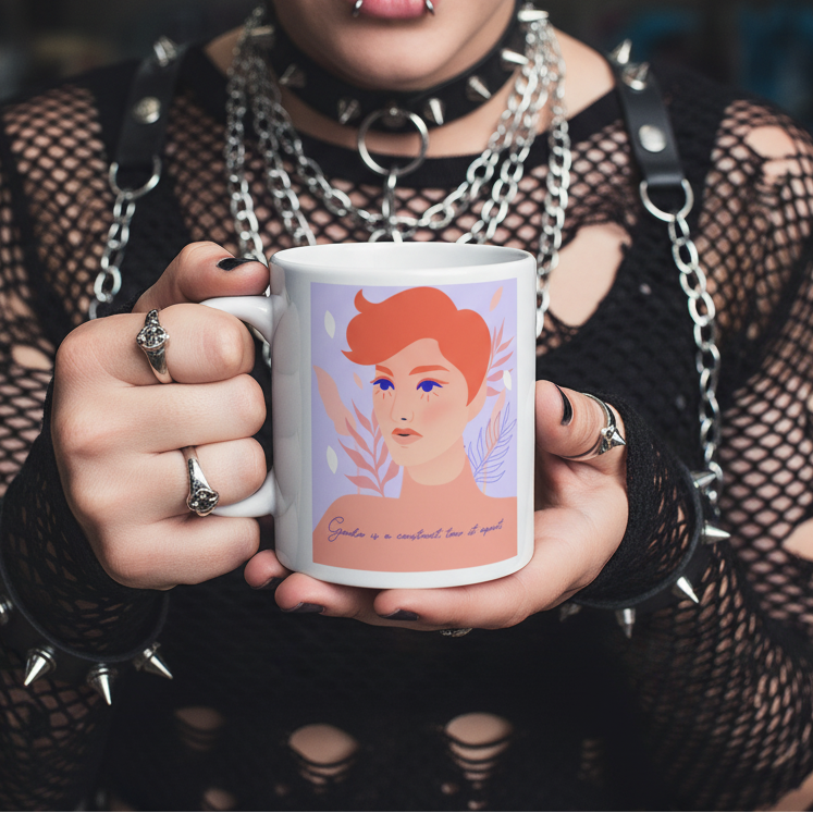 A person with a gothic/punk style holds the Gender Is A Construct Tear It Apart mug, featuring a red-haired face illustration with the empowering phrase, embodying bold queer self-expression and pride.