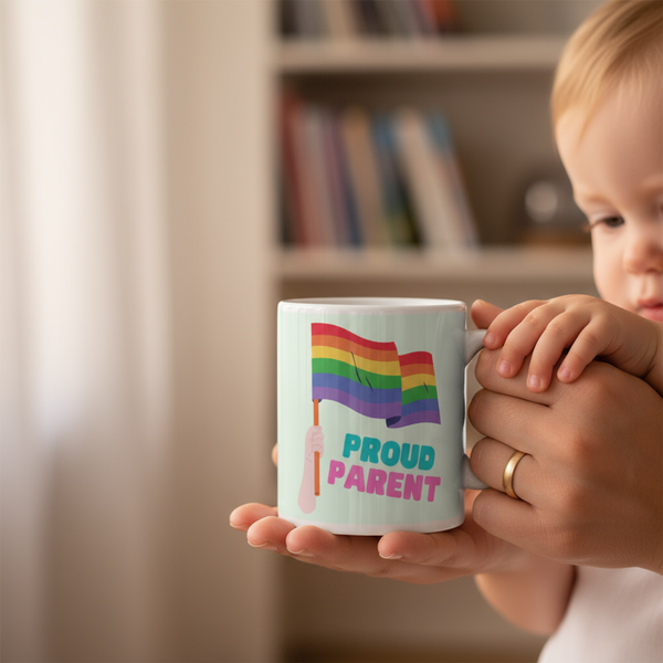 Hands hold a mint mug reading “PROUD PARENT,” with two rainbow flags and a child beside it
