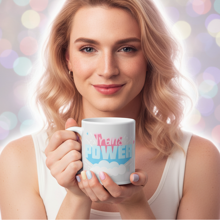 A light-skinned person joyfully holds the Stand Proud Trans Power Mug, featuring pastel pink and blue lettering. This sturdy, glossy ceramic mug celebrates LGBTQIA+ pride and self-expression.
