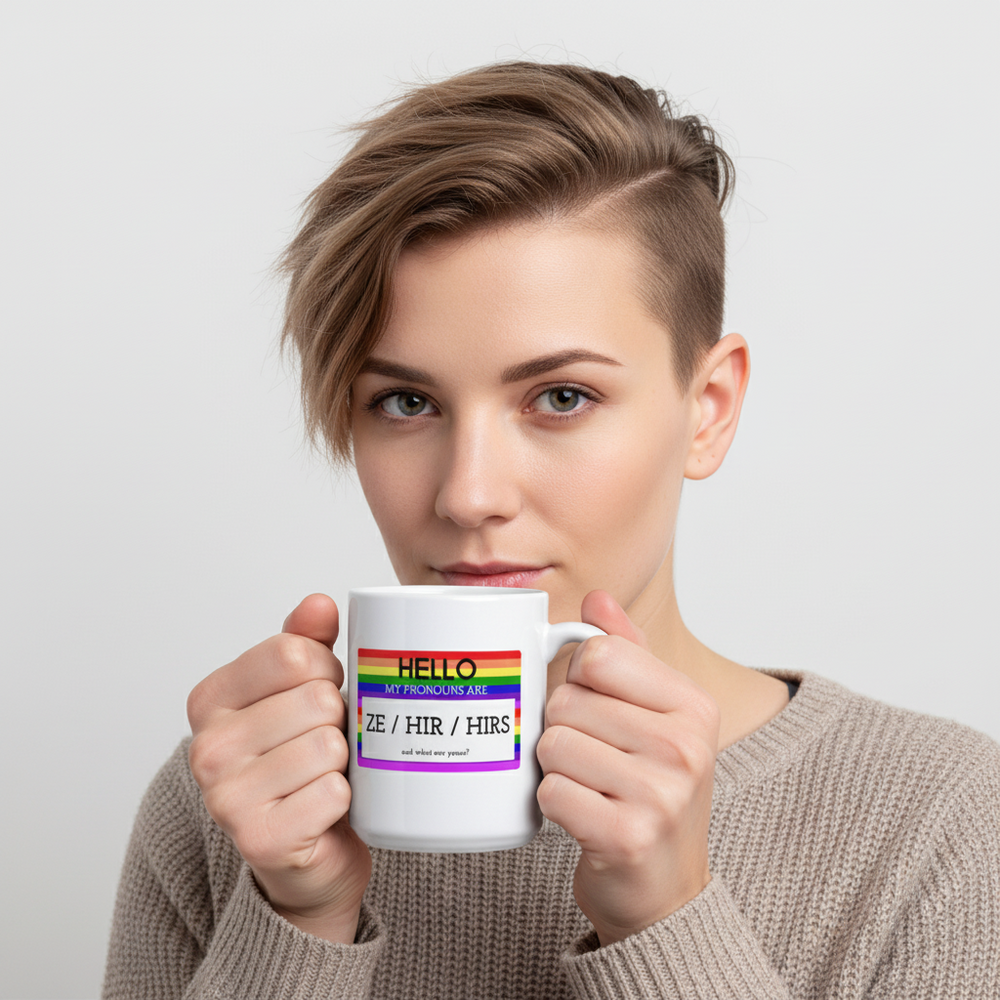Person holding a white mug labeled “HELLO MY PRONOUNS ARE ZE / HIR / HIRS”