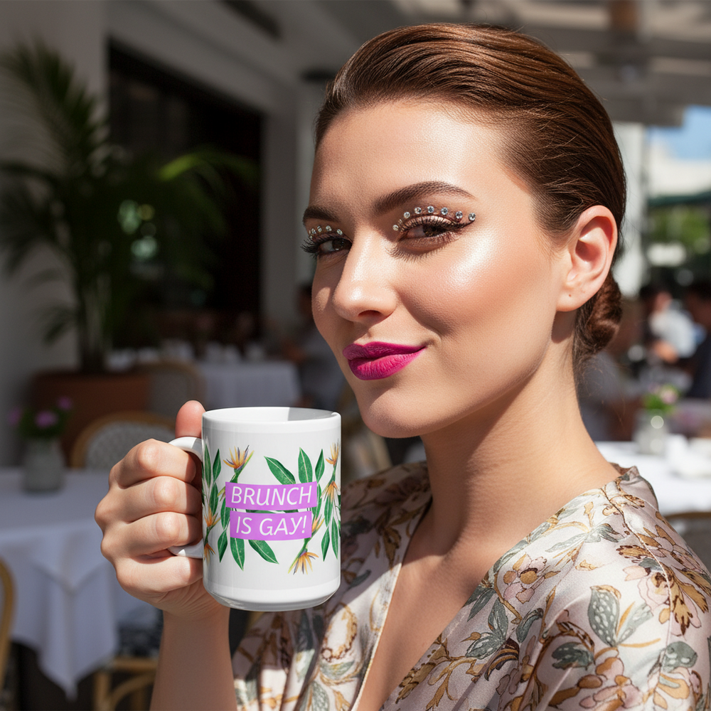 At brunch, a person holds a white floral mug reading “BRUNCH IS GAY!”