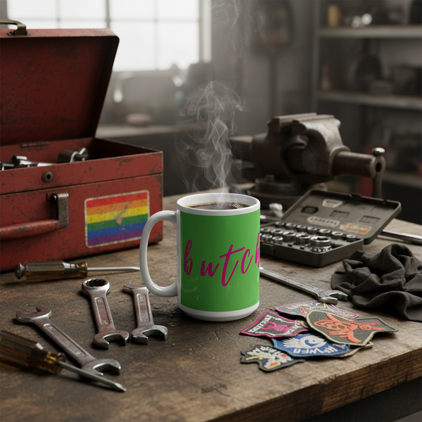 The Butch Mug sits proudly on a workbench amid tools, exuding bold queer energy with its pink script on green, embodying pride and self-expression. Perfect for coffee, tea, or wine.