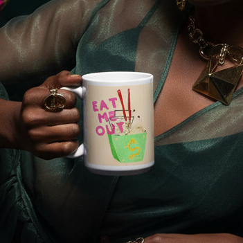 Hand holding the Eat Me Out Mug, featuring a playful graphic of a green takeout box with noodles and bold pink text, embodying joyful queer energy and self-expression from Queer In The World.