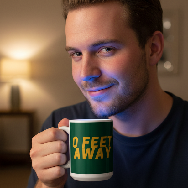 Young man holding a Zero Feet Away Grindr Mug, smiling confidently. This dark green mug with bold yellow text celebrates LGBTQIA+ pride and self-expression, perfect for coffee or tea moments.