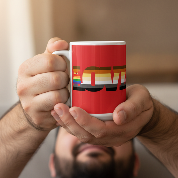 Person holding a Gay Bear Love Mug, featuring LOVE in a rainbow-striped font symbolizing LGBTQ+ pride. The red ceramic mug is durable, microwave and dishwasher safe, embodying vibrant queer self-expression.