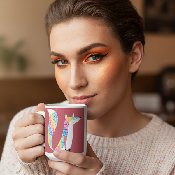 Person holds a pink mug with a colorful glittery fox illustration