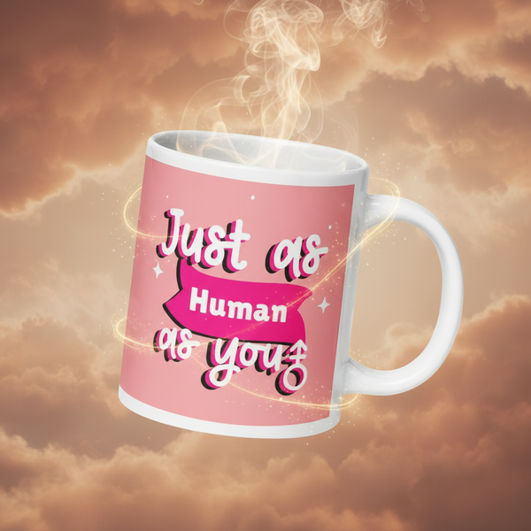 White-handled Just As Human As You Mug with a pink design and slogan, exuding steam and magic swirls, reflecting queer pride and inclusivity in a dreamy, empowering setting.