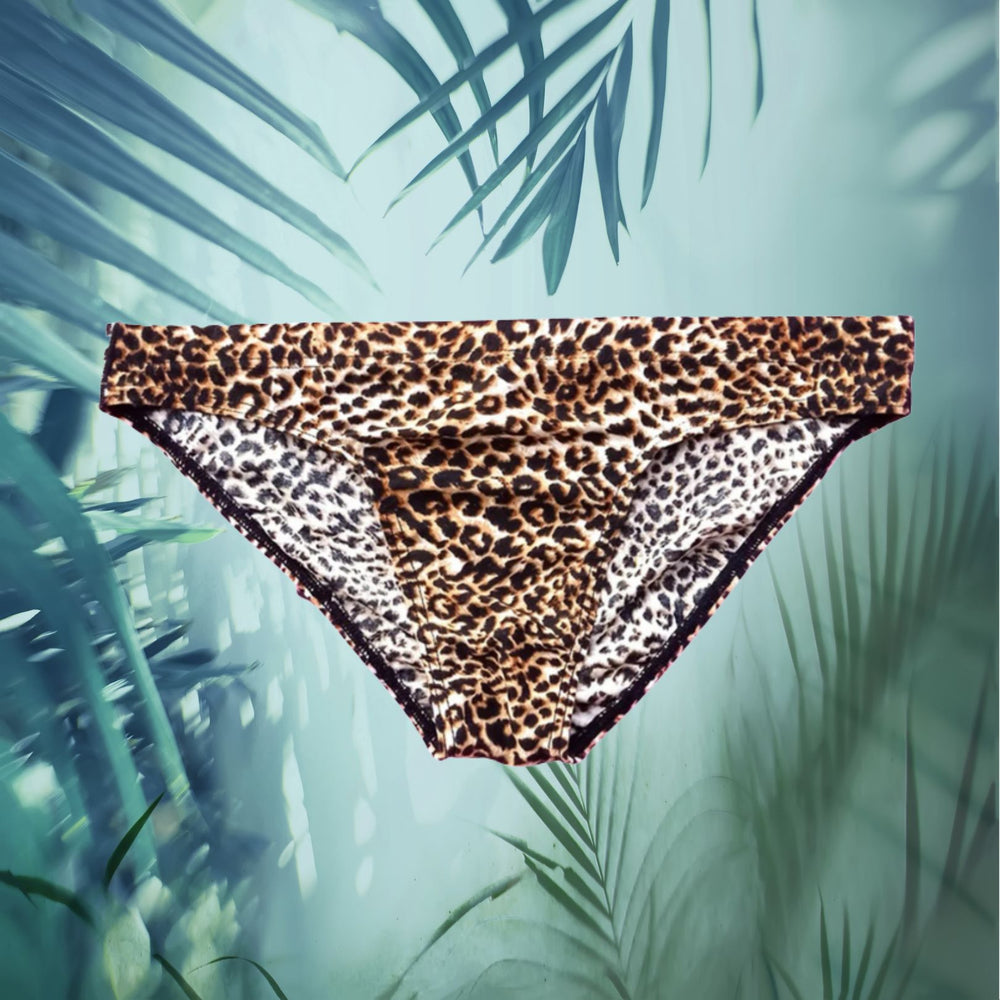 Front-facing leopard-print men's briefs suspended against a tropical leaf background