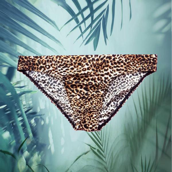 Front-facing leopard-print men's briefs suspended against a tropical leaf background