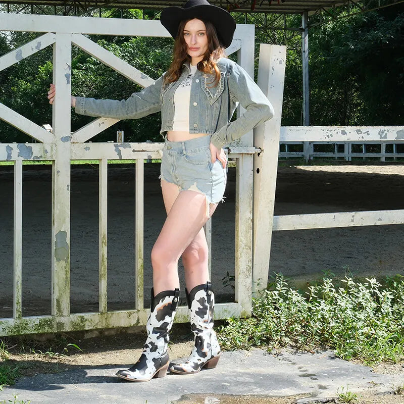 Model wearing black-and-white cow-print calf-length Western boots outdoors