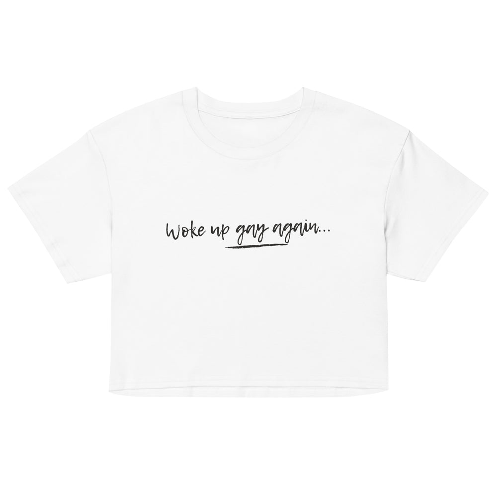 Front view of a white cropped T-shirt reading “Woke up gay again...” in black script