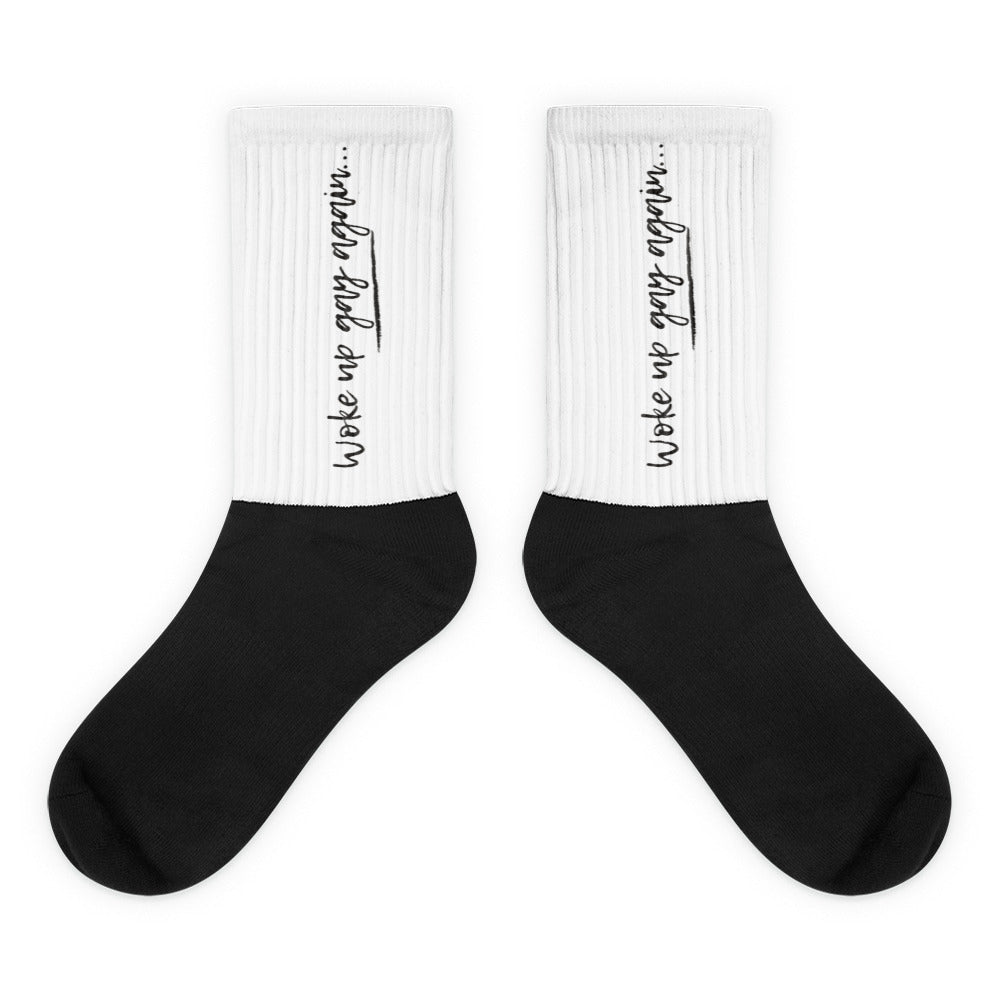 Pair of black-and-white crew socks reading “Woke up gay again…” on the cuffs