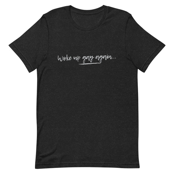 Black unisex t-shirt with “Woke Up Gay Again” in white handwritten text across the chest, laid flat on a white background.