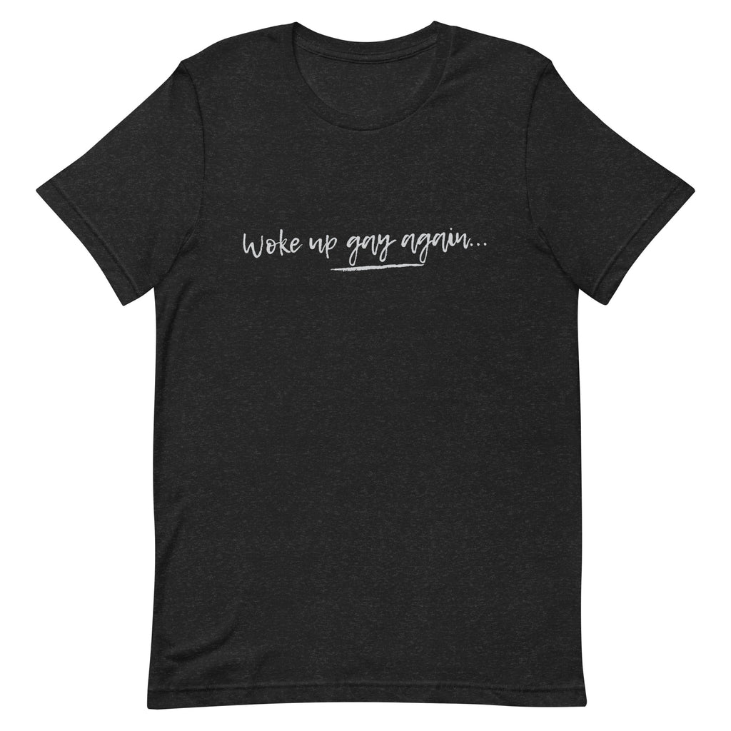 Black unisex t-shirt with “Woke Up Gay Again” in white handwritten text across the chest, laid flat on a white background.