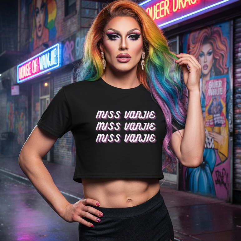 Drag performer wearing Miss Vanjie Crop Top with Miss Vanjie printed thrice, showcasing dramatic flair and rainbow hair, embodying queer confidence and self-expression on a neon-lit street.