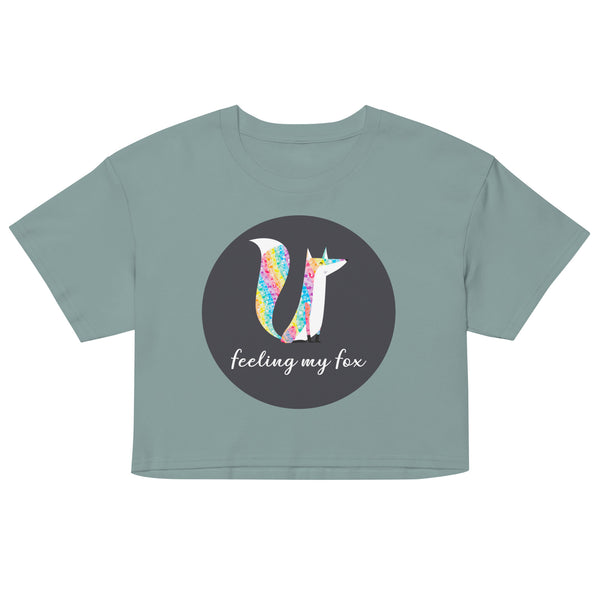 Front view of a sage green crop top with a colorful fox graphic and “feeling my fox” text