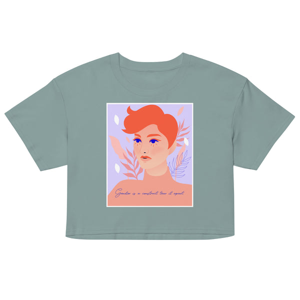 Front view of a sage green crop top with an illustrated red-haired face and text, “Gender is a construct, tear it apart.”