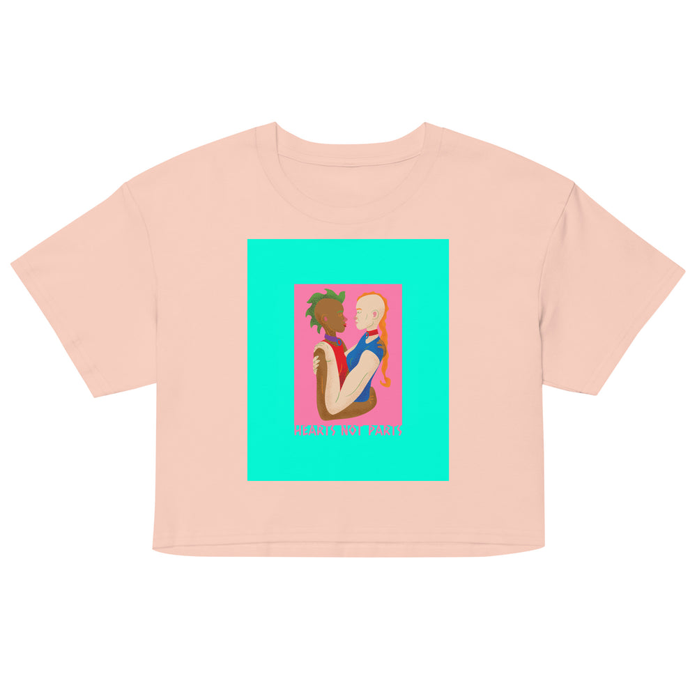 Front view of a pale pink crop top with colorful artwork of two embracing figures and “HEARTS NOT PARTS” text
