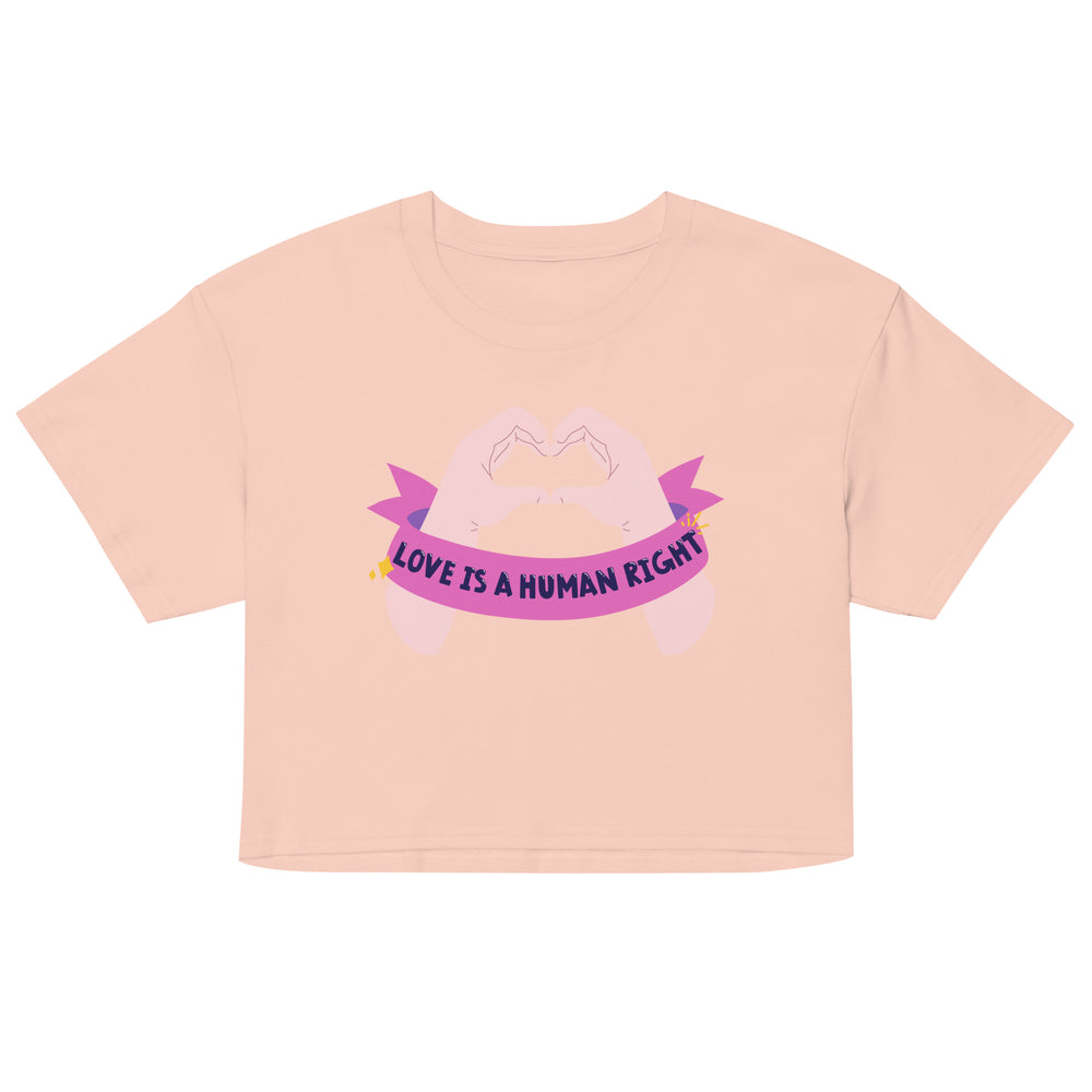 Front-view peach crop top with a pink heart-hands graphic and “LOVE IS A HUMAN RIGHT” banner