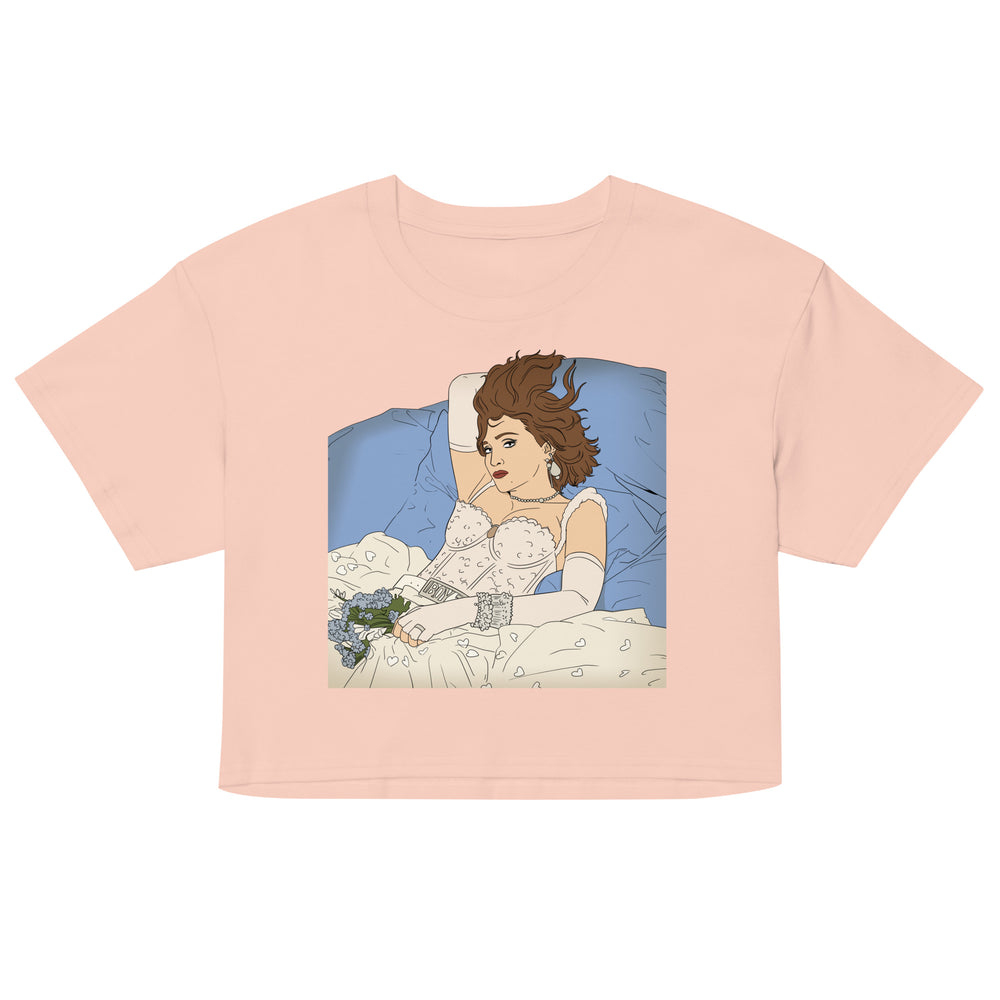 Front view of a blush-pink crop top with a vintage-style woman-in-bed illustration