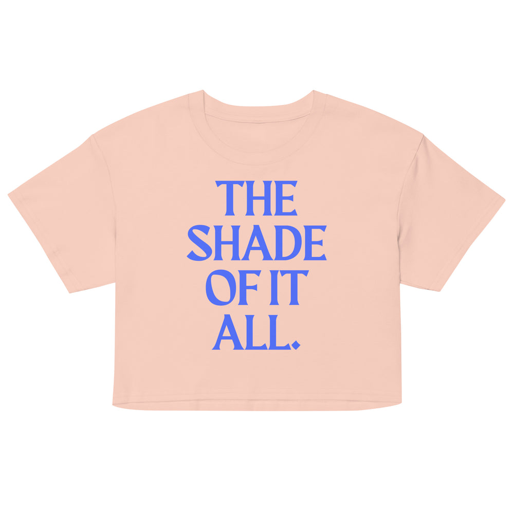 Front view of a peach cropped T-shirt with blue text reading “THE SHADE OF IT ALL.”