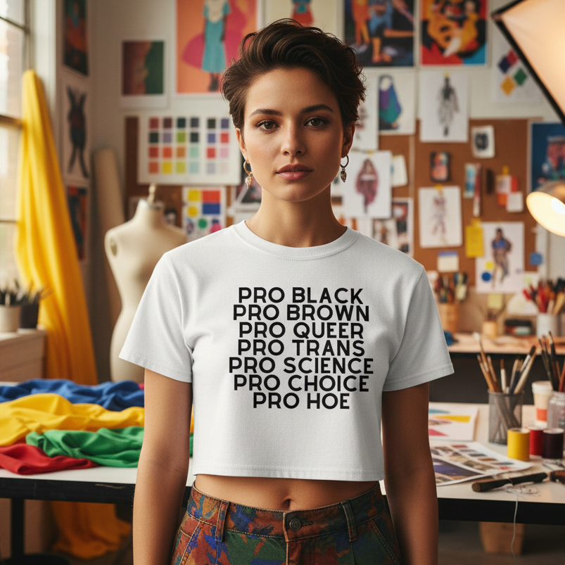 Pro Hoe Crop Top: loose white shirt, bold black text reads "Pro Black, Pro Brown, Pro Queer, Pro Trans..." in an artsy studio.