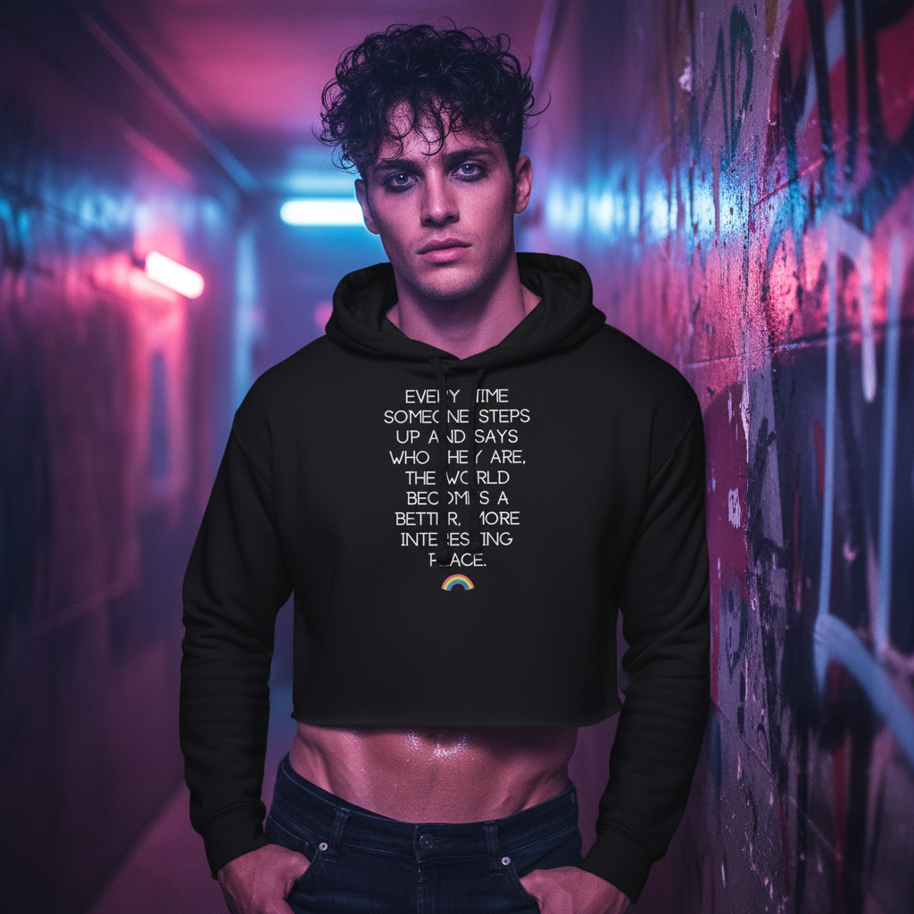 Every Time Someone Stands Up" crop hoodie on a young man with curly hair, in neon-lit graffiti; queer-affirming, pride-themed fashion.