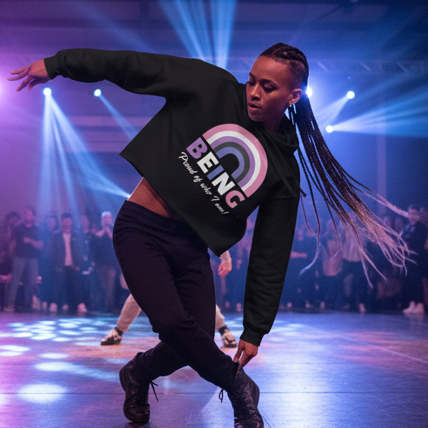 Black crop hoodie with a rainbow and "BEING Proud to be who I am" slogan, worn by a braided dancer under queer stage lights.