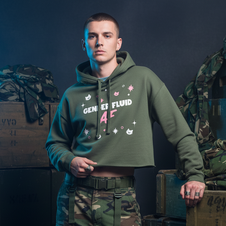 A young person models the Gender Fluid AF Crop Hoodie, an olive-green hoodie with GENDER FLUID AF text. Paired with camo cargo pants, it embodies bold, playful self-expression and proud queer identity.