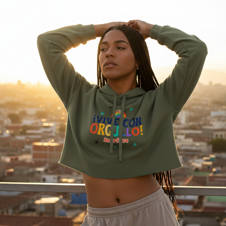 Crop hoodie with bold Spanish text “¡Vive Con Orgullo! Amor Libre,” rocked by a femme with braids at sunset, serving queer pride.