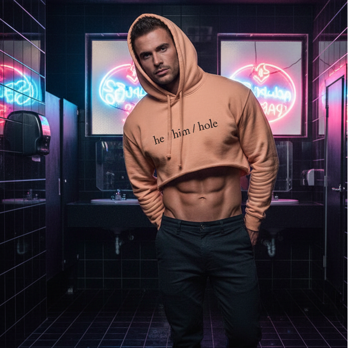 He / Him / Hole Crop Hoodie in a neon-lit, black-tiled restroom; queer man with short hair flaunts abs and dark pants.