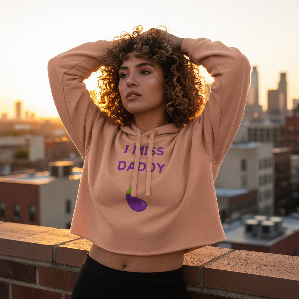 I Miss Daddy Crop Hoodie worn by a curly-haired woman on a sunset rooftop; blurred city lights pop, repping bold queer style.