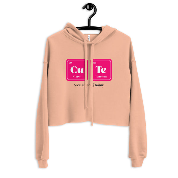 Front view of a peach cropped hoodie on a hanger with a Cu and Te graphic and partial text