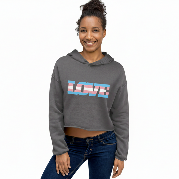 Young woman wearing the Transgender Love Crop Hoodie, a charcoal-gray hoodie with LOVE in transgender-pride colors, paired with dark blue jeans, showcasing queer pride and self-expression.