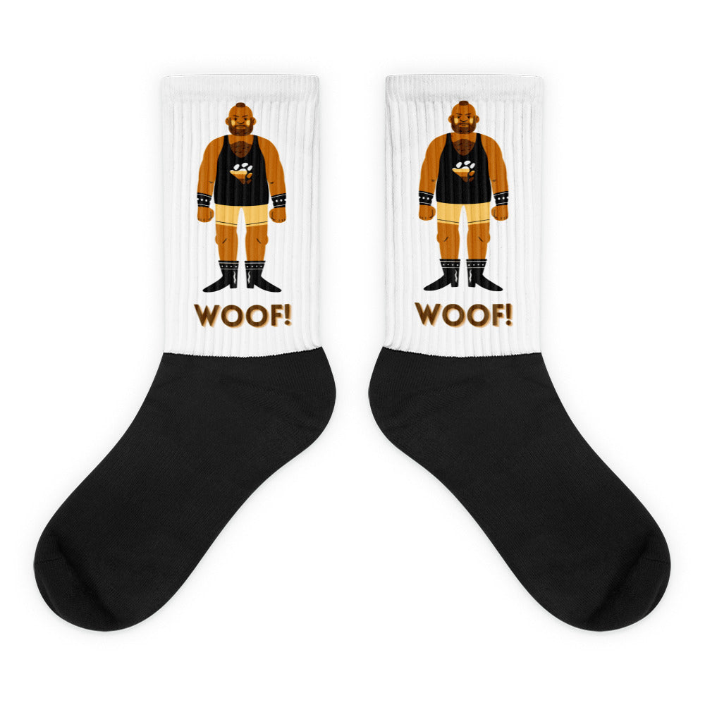 Pair of black-and-white crew socks with a muscle-man graphic and “WOOF!” text