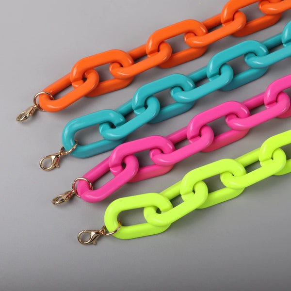 Close-up of four chunky acrylic chain necklaces in orange, turquoise, pink, and neon yellow