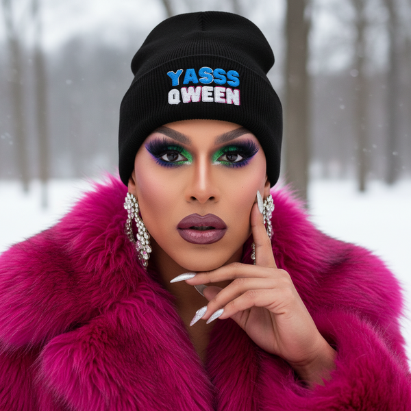 Yasss Qween Cuffed Beanie with bold black design, magenta faux fur coat, glam nails, and queer makeup in snowy LGBTQ+ vibe.