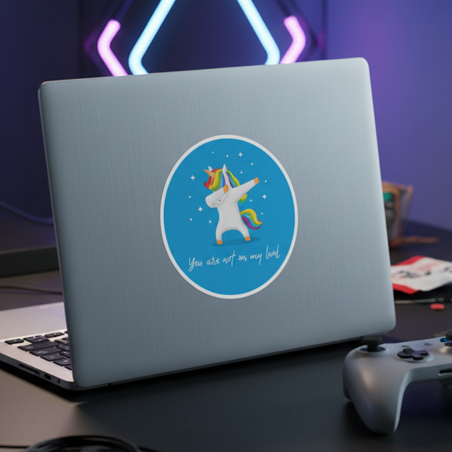 Silver laptop with a "You Are Not On My Level" unicorn sticker under stars, plus game controller, mouse