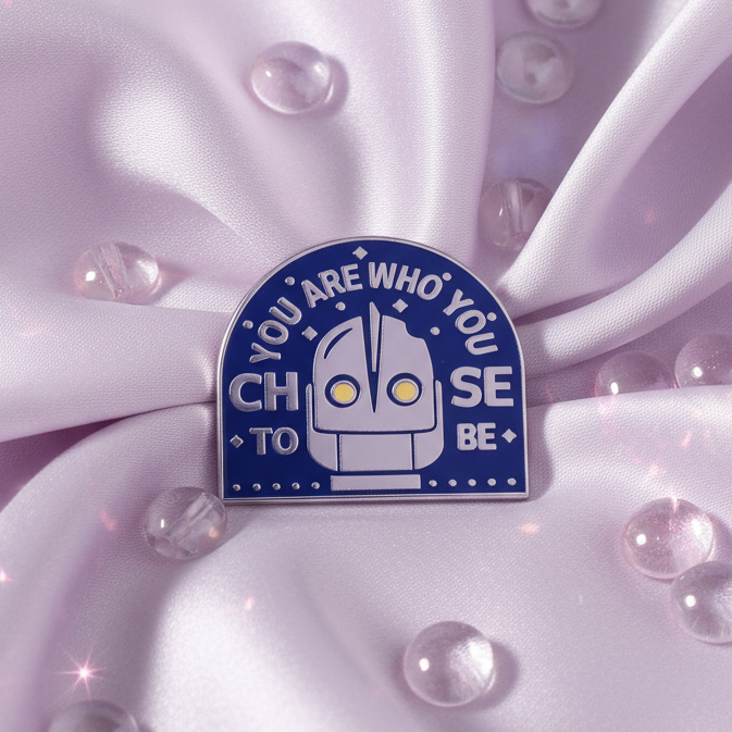 Blue enamel pin reading “YOU ARE WHO YOU CHOOSE TO BE,” with a robot face