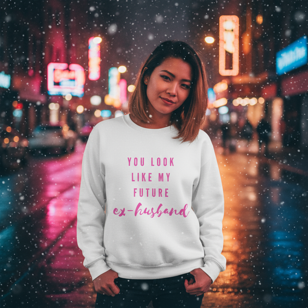 Person wearing a white sweatshirt reading “You Look Like My Future Ex-husband” in a snowy neon-lit street