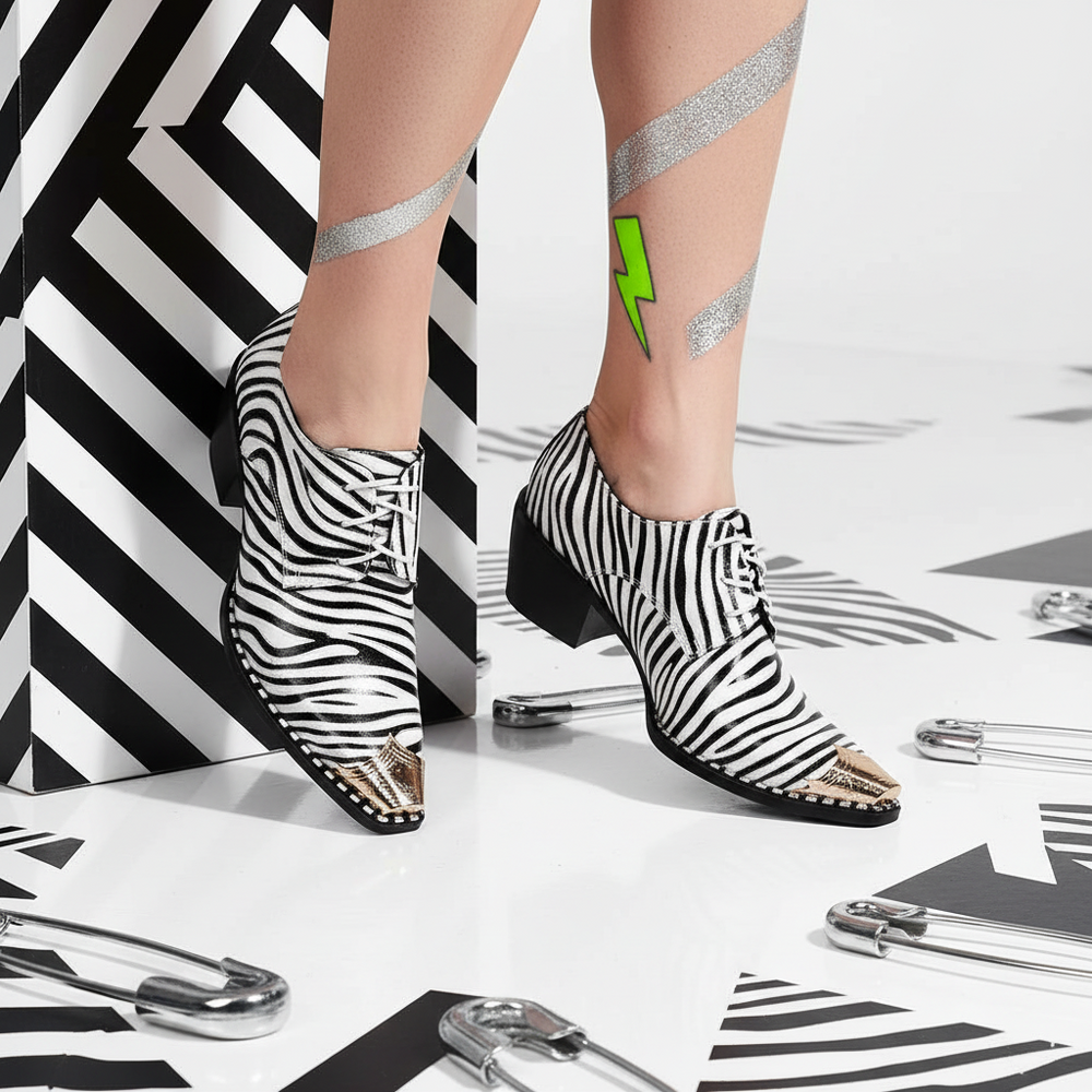 Zebra-print lace-up dress shoes with gold metal toe caps on a model; their glittery