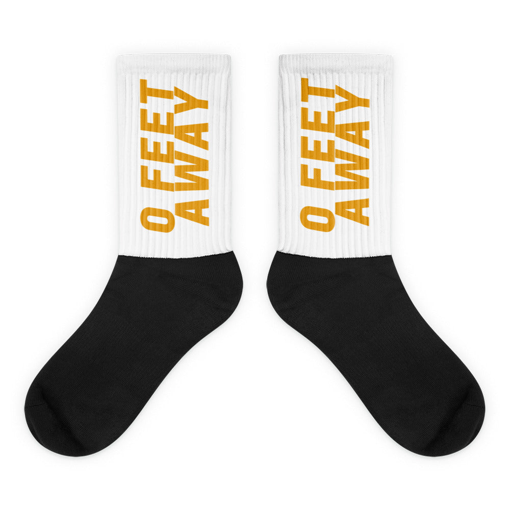 Pair of black-and-white socks with mustard-yellow “0 FEET AWAY” text