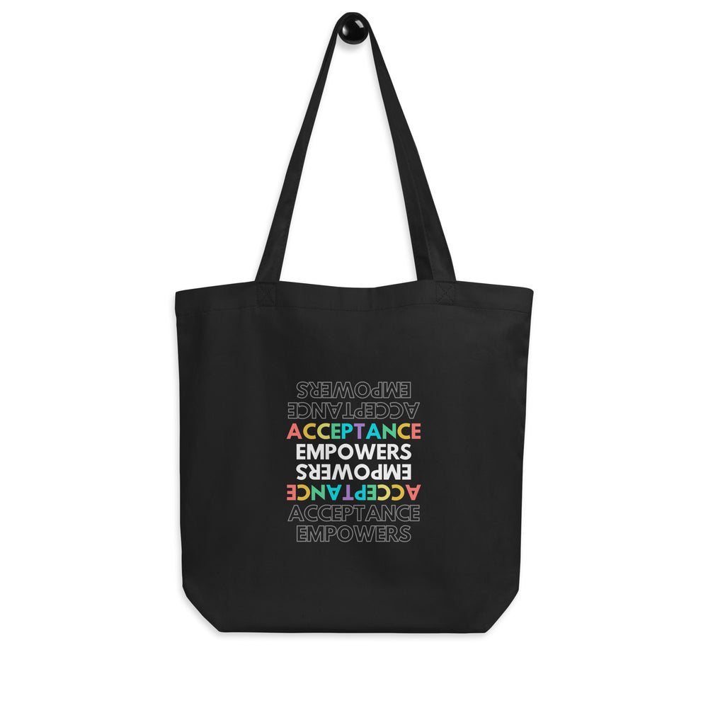 Front view of a black tote bag reading “ACCEPTANCE EMPOWERS” in repeated orientations