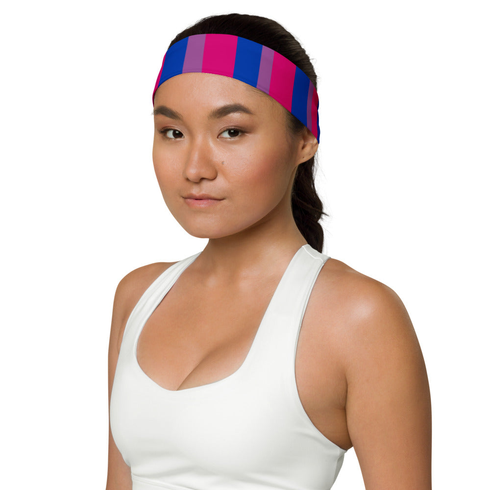 bi fan: A person with short curls and a soft smile wears a striped Bisexual Pride headband—pink, purple, blue